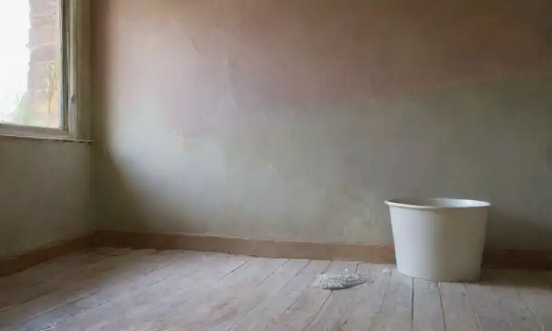 Una habitación iluminada con luz suave y cálida, donde se realizan reparaciones en la pared mientras se prepara para combatir el moho
