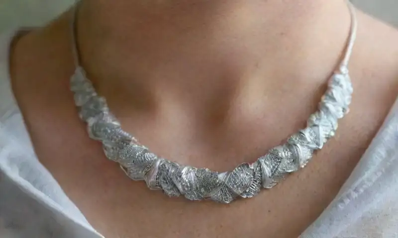 Un collar de plata pulido brilla bajo la luz suave