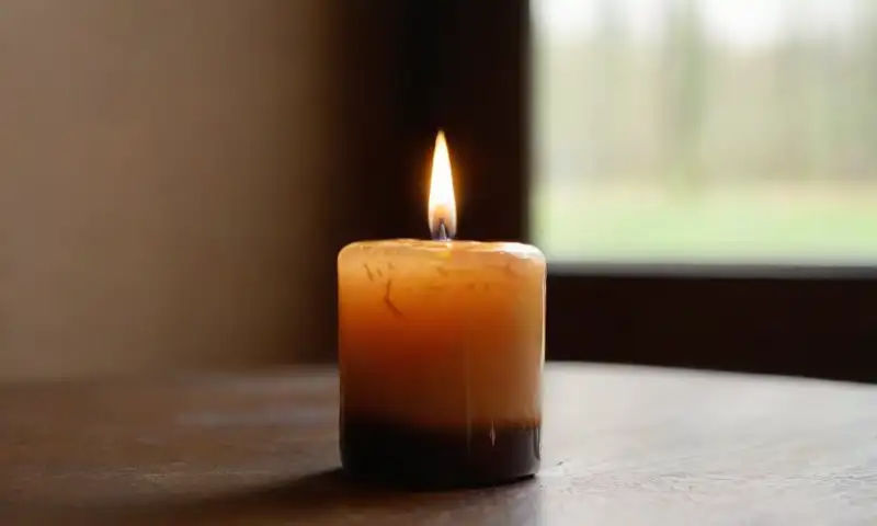 Una suave llama de vela ilumina un ambiente íntimo y espiritual, junto a una figura de llama decorativa, creando un juego de luces y sombras en un entorno acogedor
