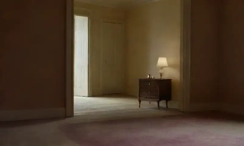 Una habitación tenue y acogedora, llena de sombras y objetos personales, evoca una atmósfera introspectiva de caos y calma