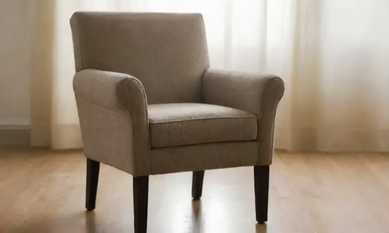 Una silla de tela desgastada con manchas oscuras y suavemente descolorida