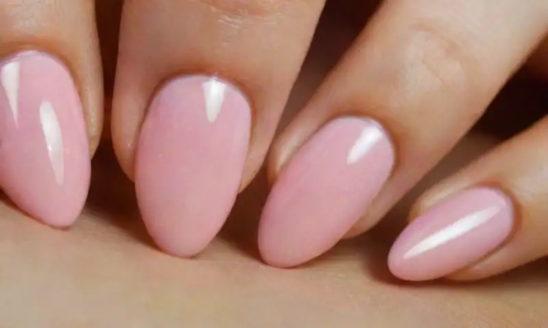 Uñas elegantes con forma almendrada, acabado brillante en tonos degradados de rosa, en un ambiente sereno y bien iluminado