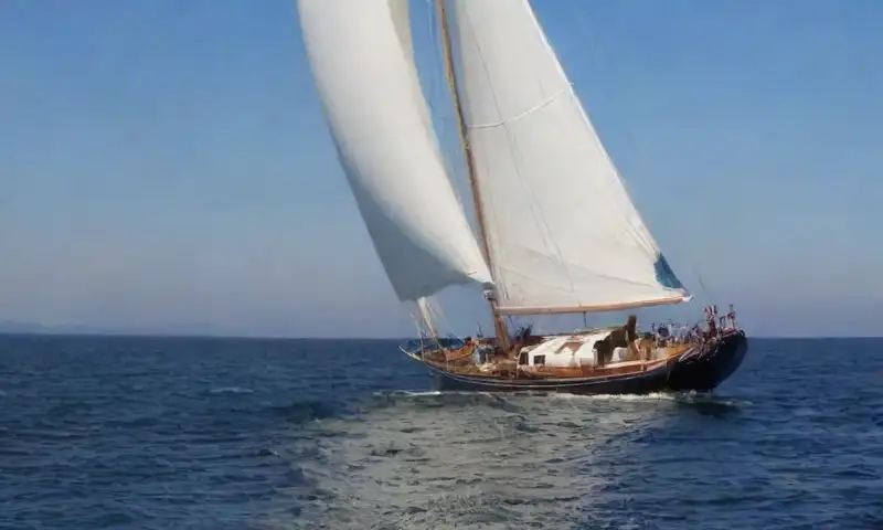 Una vela azul marino ondea suavemente en un océano sereno, con detalles de luz y sombra que crean una composición armoniosa