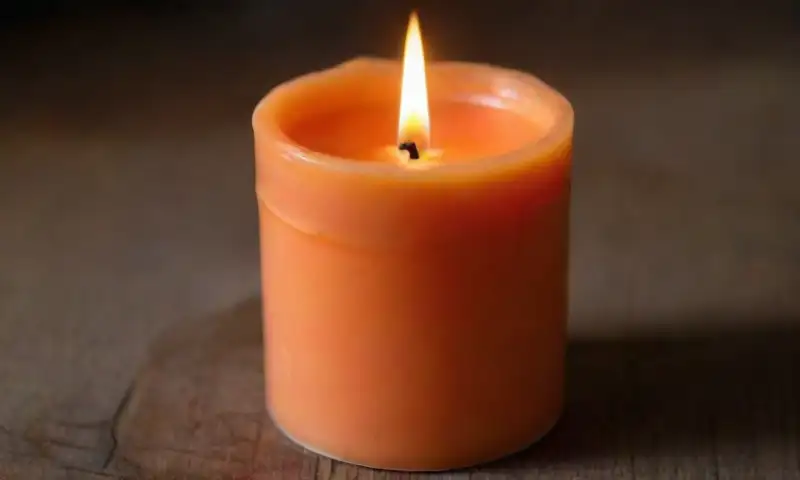 Una vela naranja brillante emite una suave luz cálida que crea un ambiente sereno y acogedor