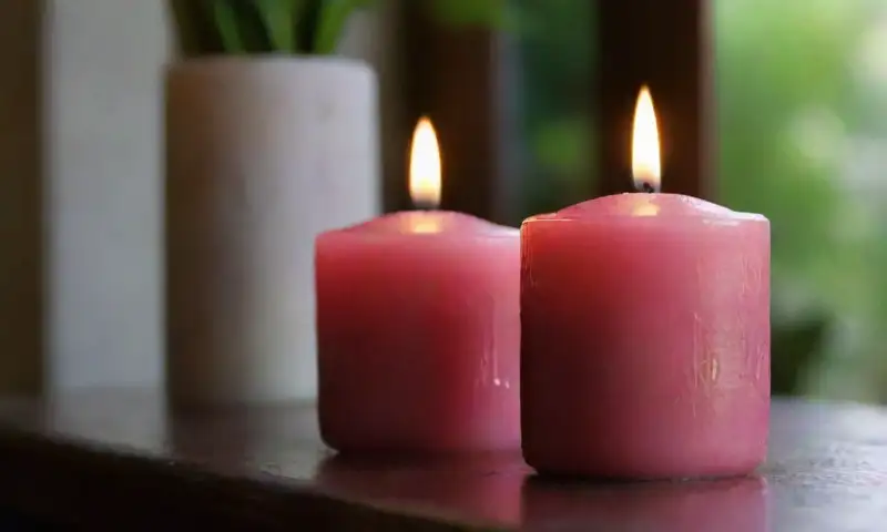 Un primer plano de velas de diferentes tamaños y colores sobre una mesa de madera, creando un ambiente cálido y sereno